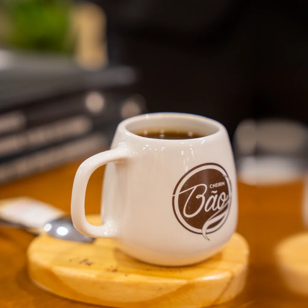 Caneca Cheirin Bão com café na mesa da unidade Anchieta